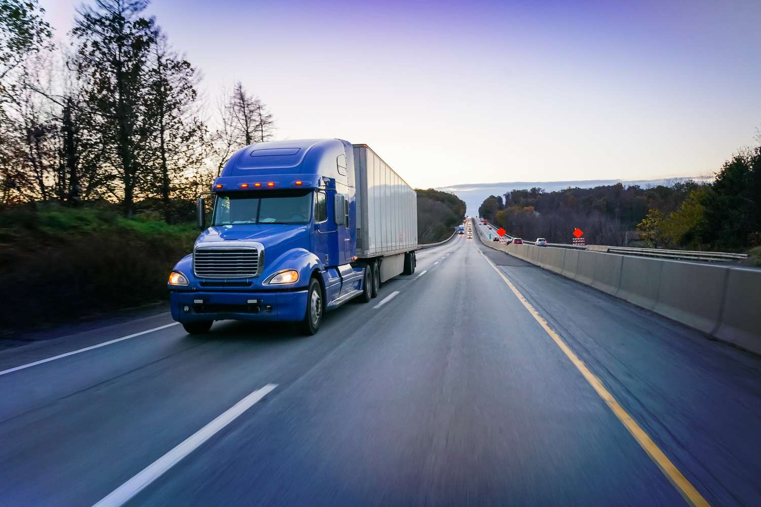 18-wheeler-blue-semi-truck-on-highway-at-dusk-932516238-af4ac2fab5f5447c9c971dad1cbdc8ca
